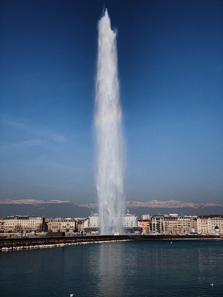 View of the iconic Jet d'Eau fountain in Geneva, against a clear blue sky.
